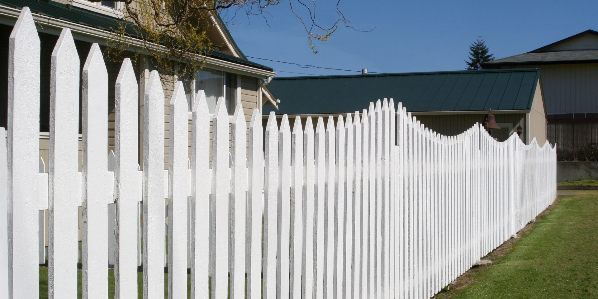 A white picket fence is in front of a house.