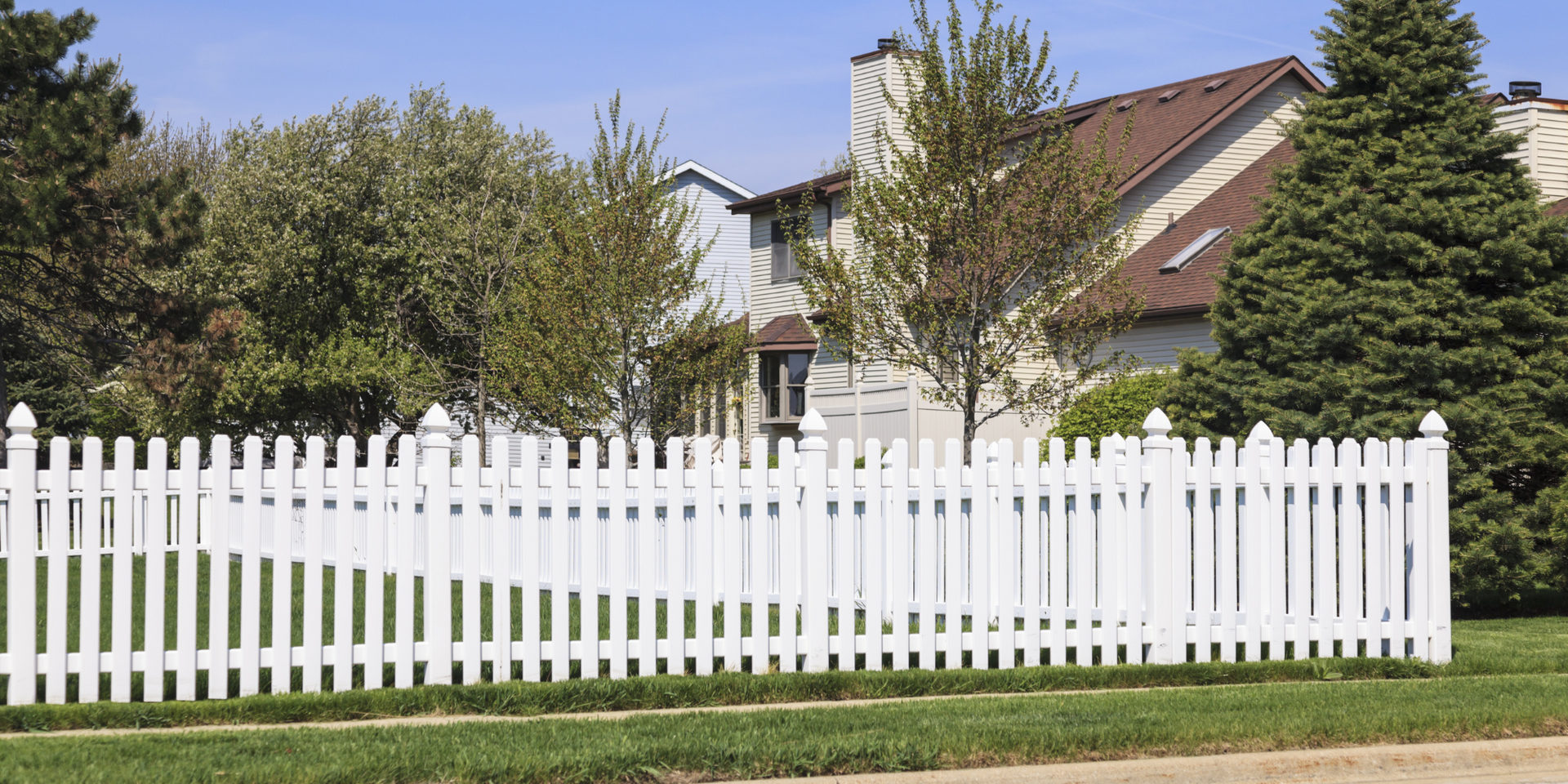 A white picket fence surrounds a house in a residential neighborhood.