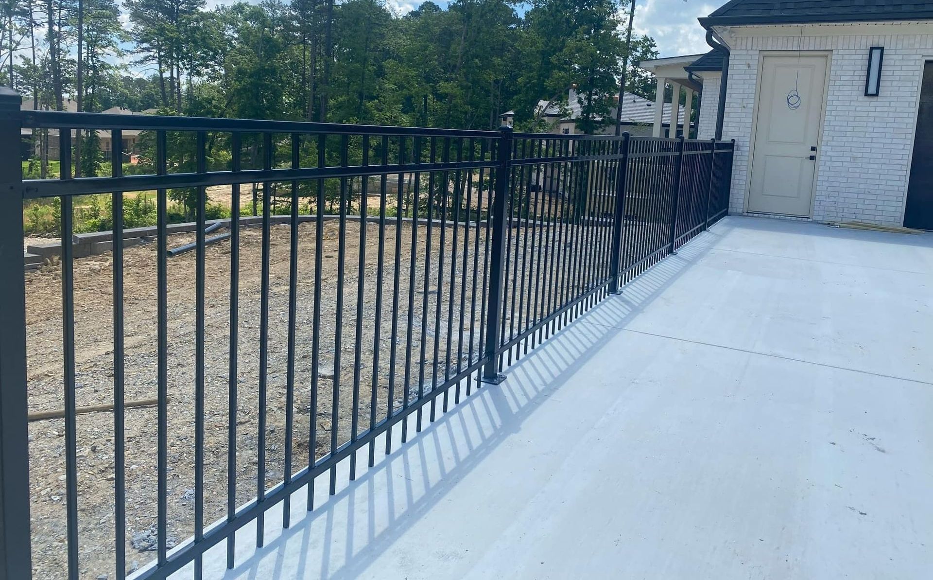 A black fence is surrounding a concrete deck.