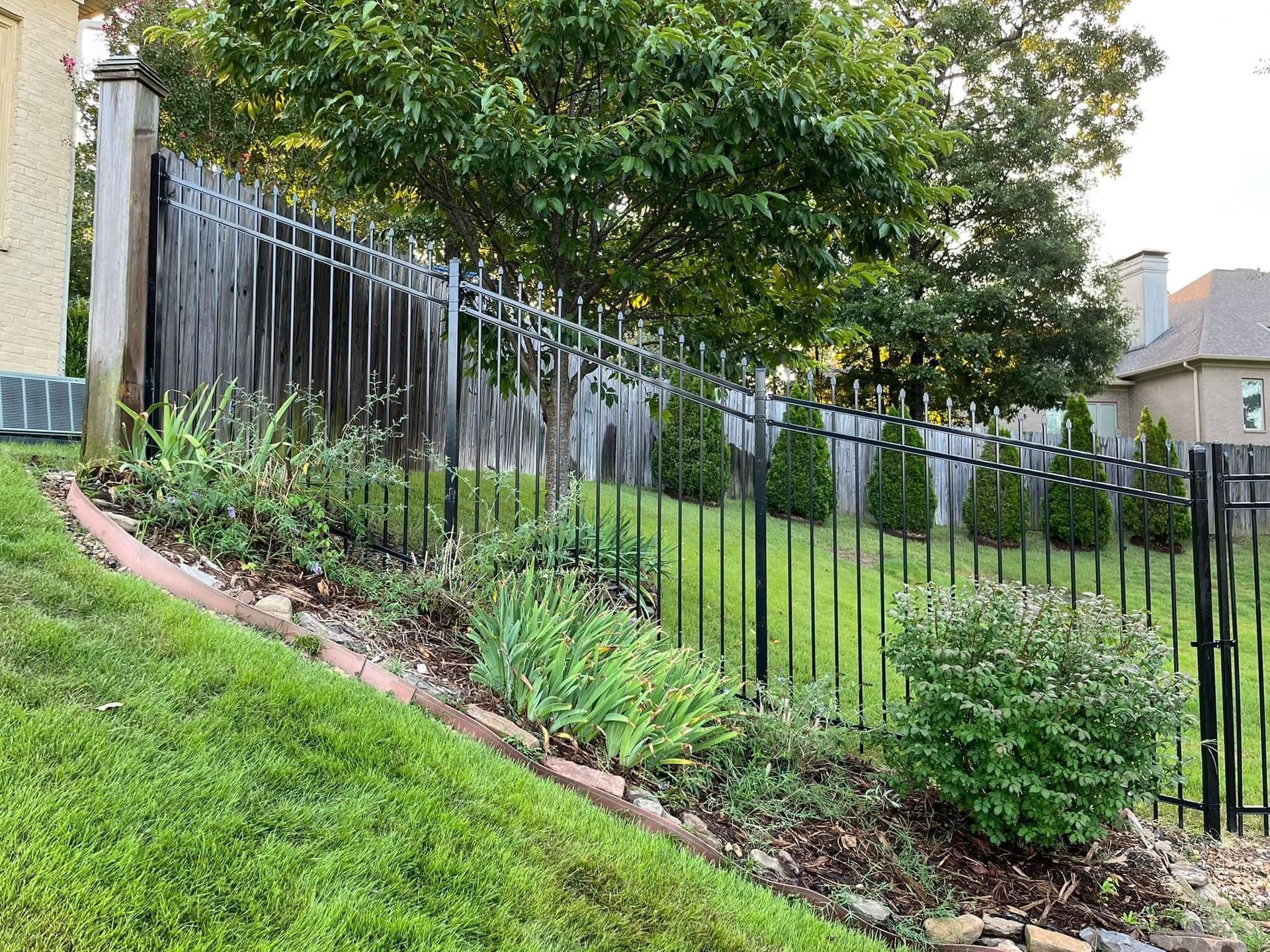 A black wrought iron fence surrounds a lush green yard.