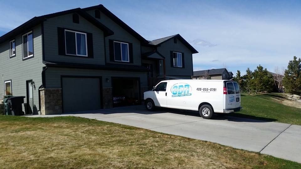 A white van is parked in front of a large house.