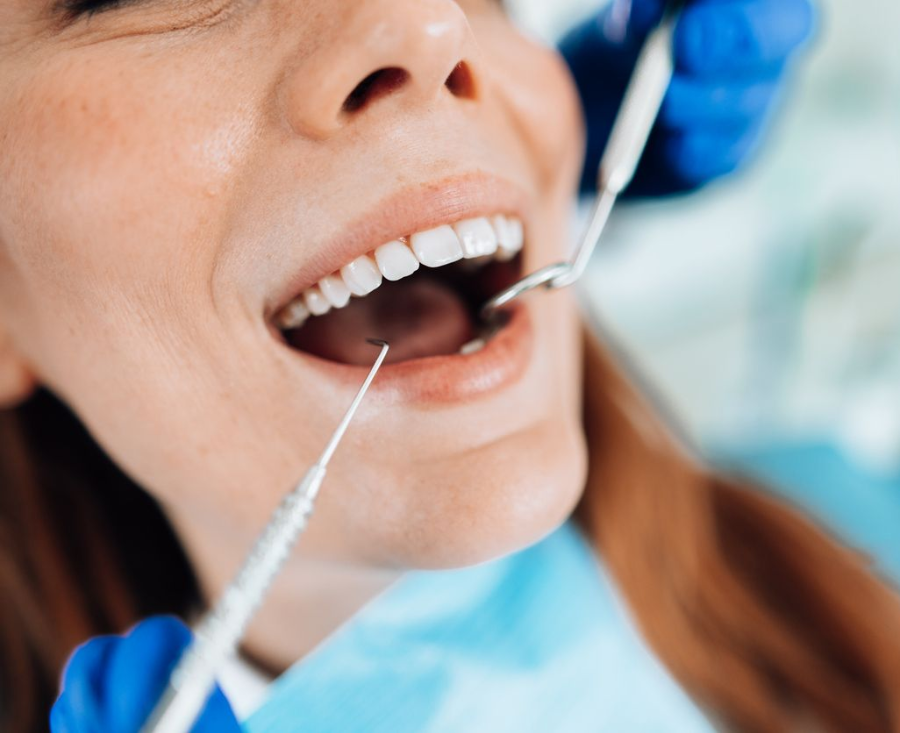 Woman in black scrubs talking to a smiling man in a dental chair. Inside a dentist's office.