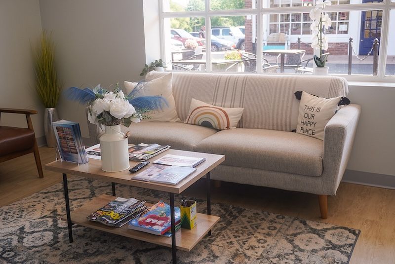 Cozy waiting area with beige couch, coffee table, and window view.