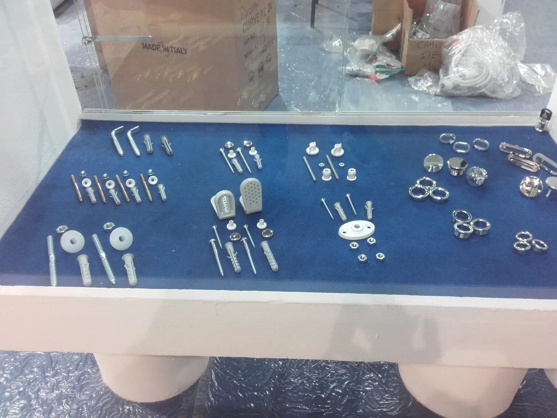 Esposizione su tavolo di un assortimento di piccoli gioielli in argento e accessori in metallo su una tovaglia blu.