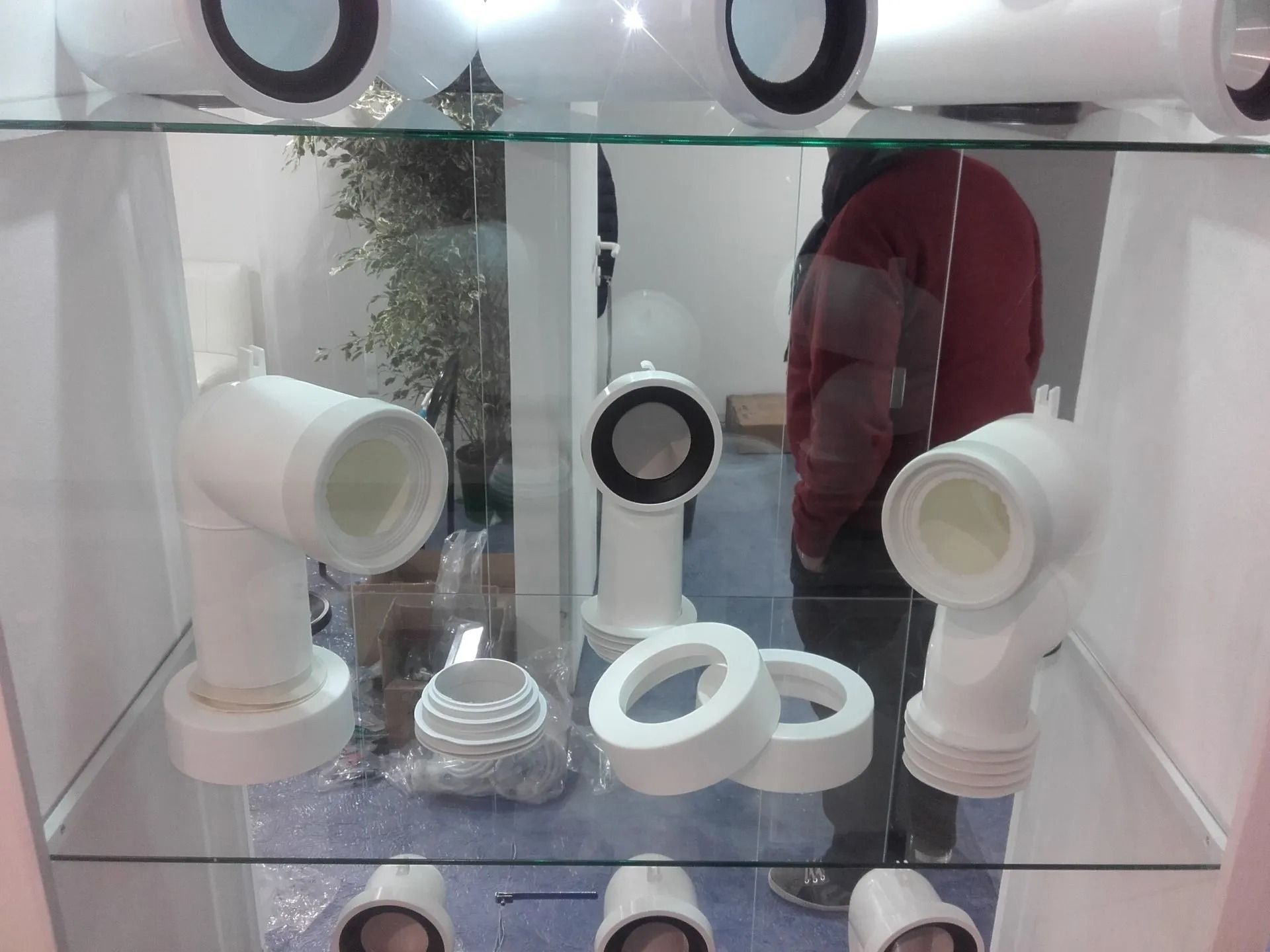 Raccordi per tubi in PVC bianco esposti su scaffali di vetro in un negozio