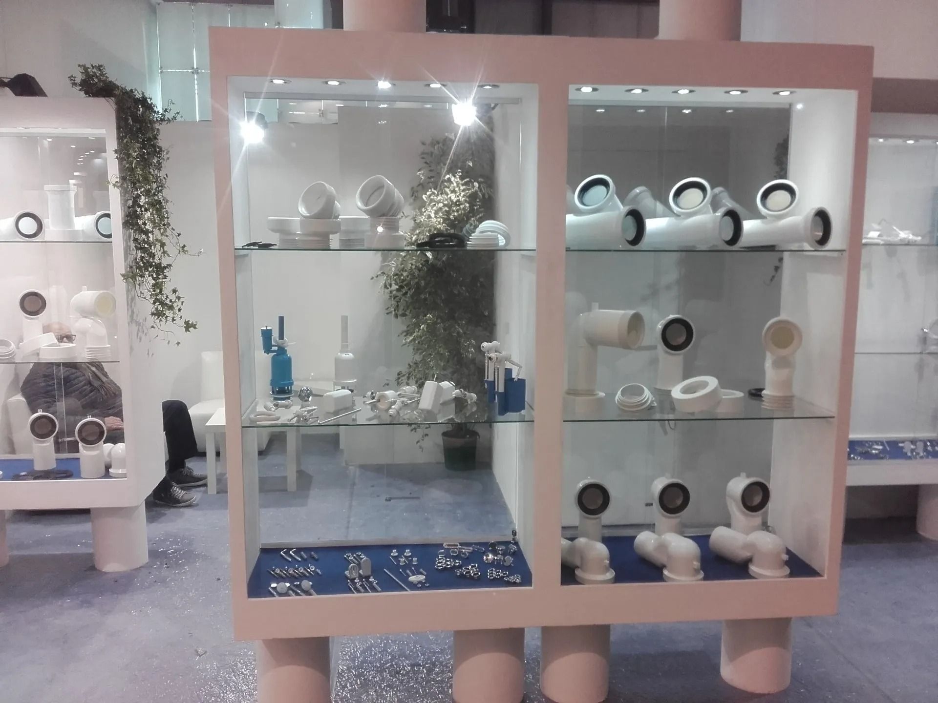 Vetrine in vetro con oggetti in ceramica in uno showroom rosa pastello.