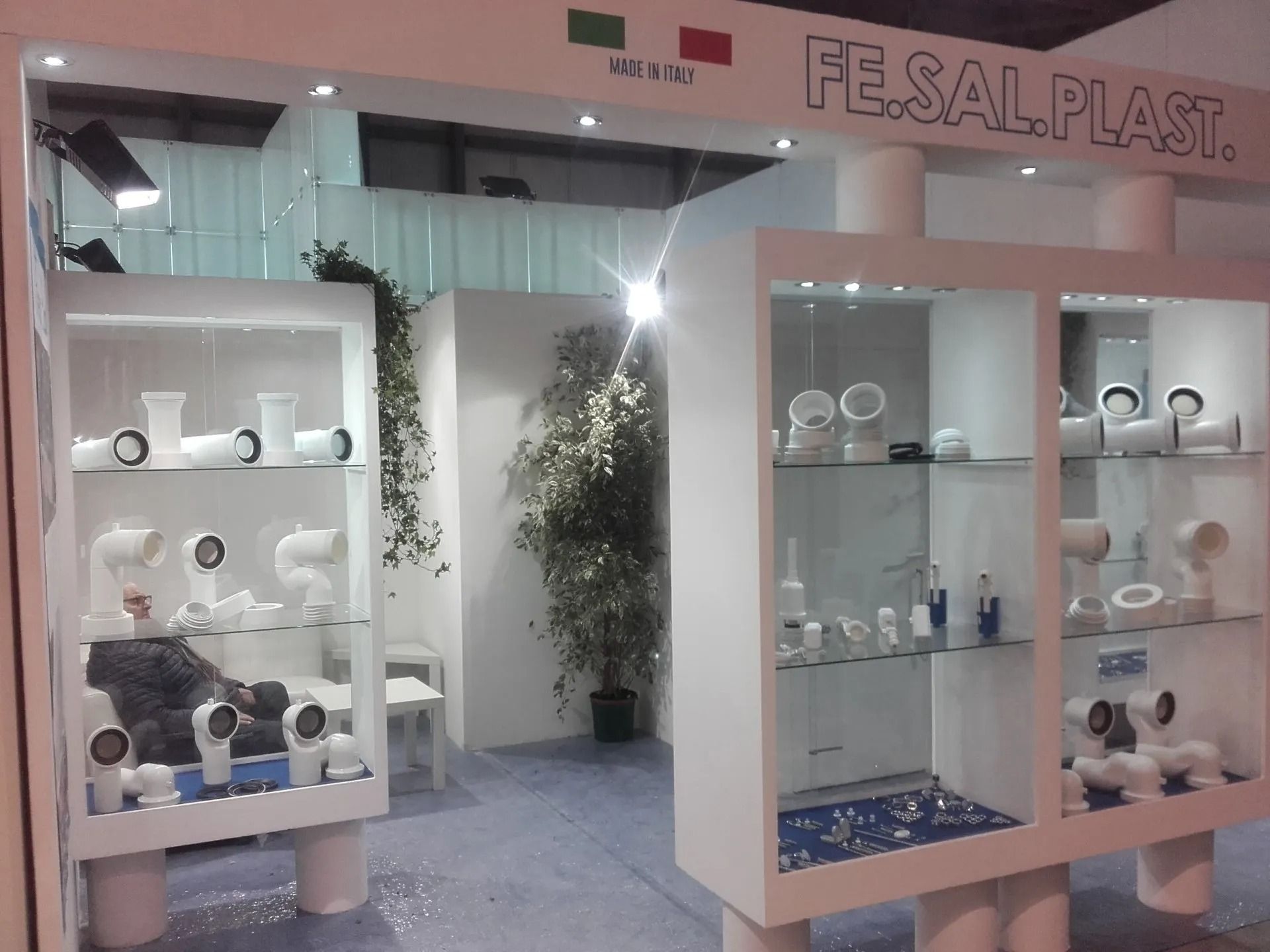 Stand fieristico con vetrine bianche e in vetro che espongono sanitari e accessori per il bagno.