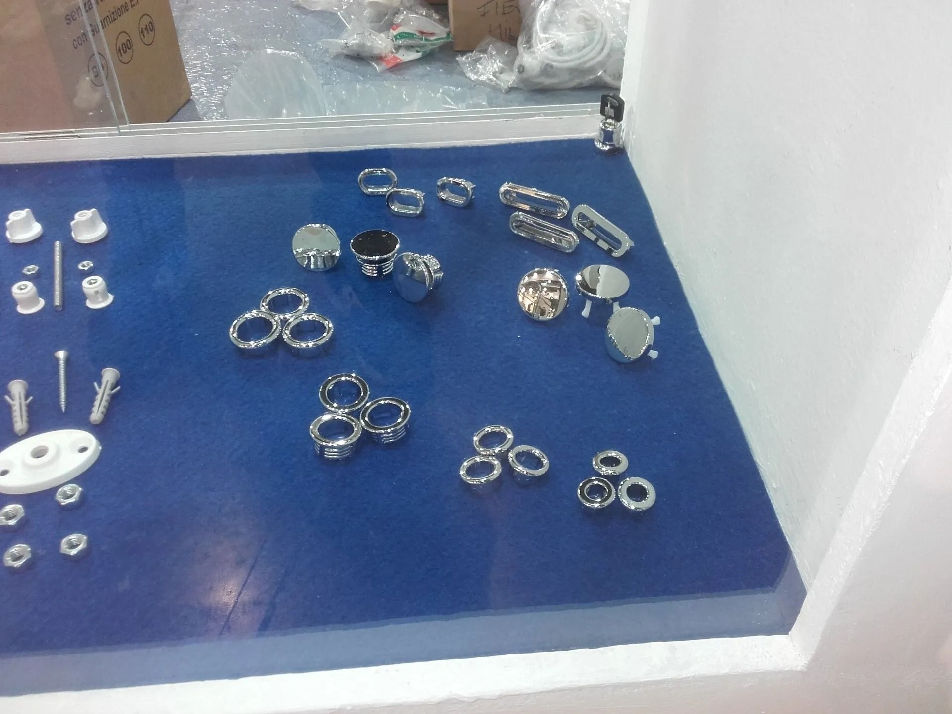 Piccoli anelli e orecchini in metallo e cristallo disposti su un vassoio blu in un negozio.