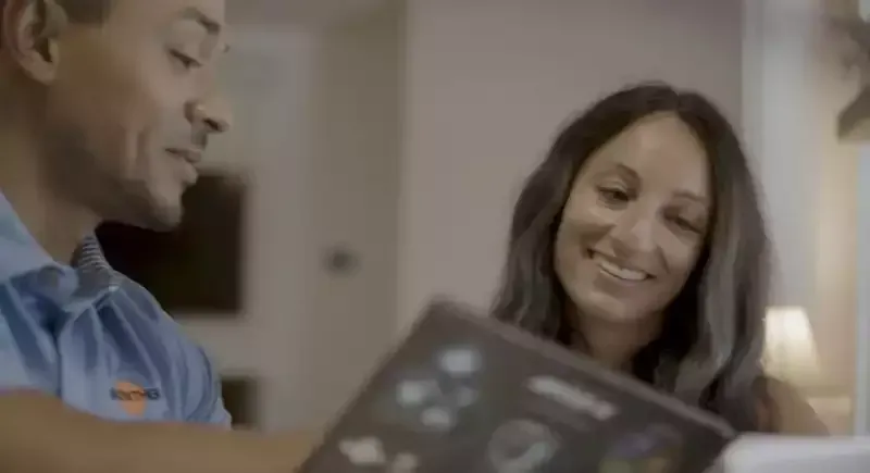 Two people smiling and talking at a table, with a tablet in the foreground