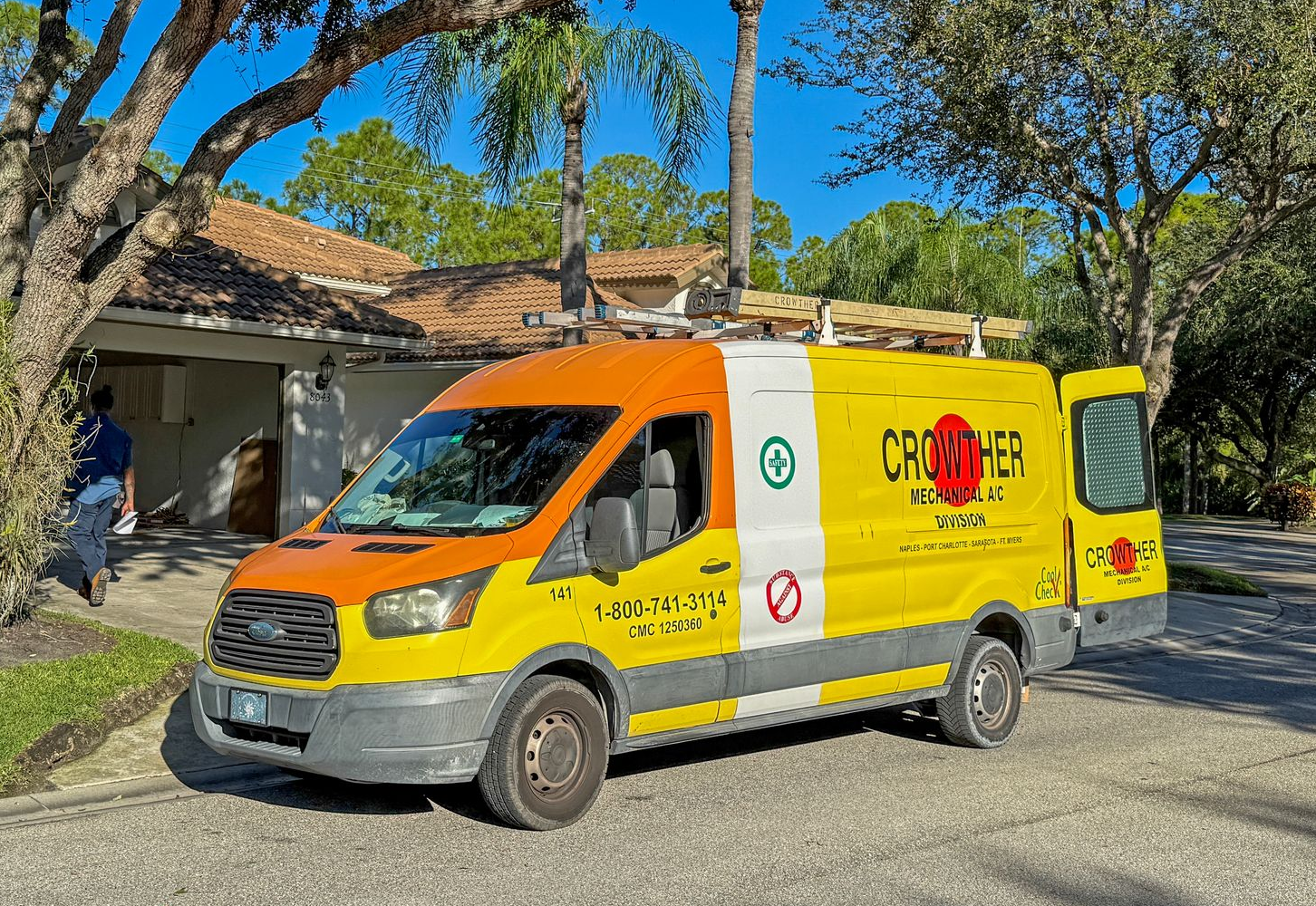Yellow-and-white service van parked on a sunny street under trees