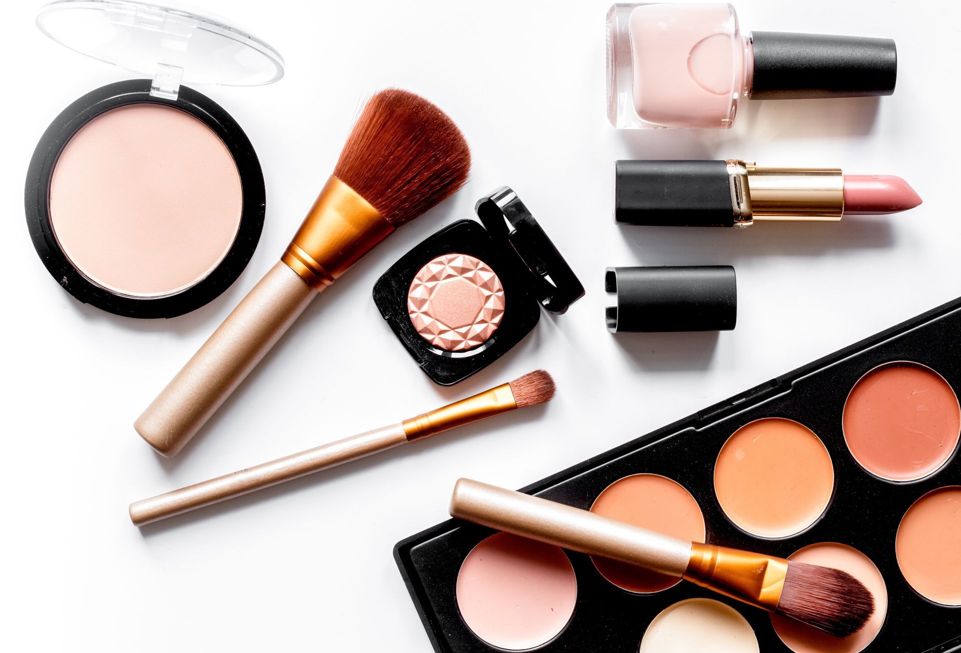 A palette of makeup and brushes on a white surface.