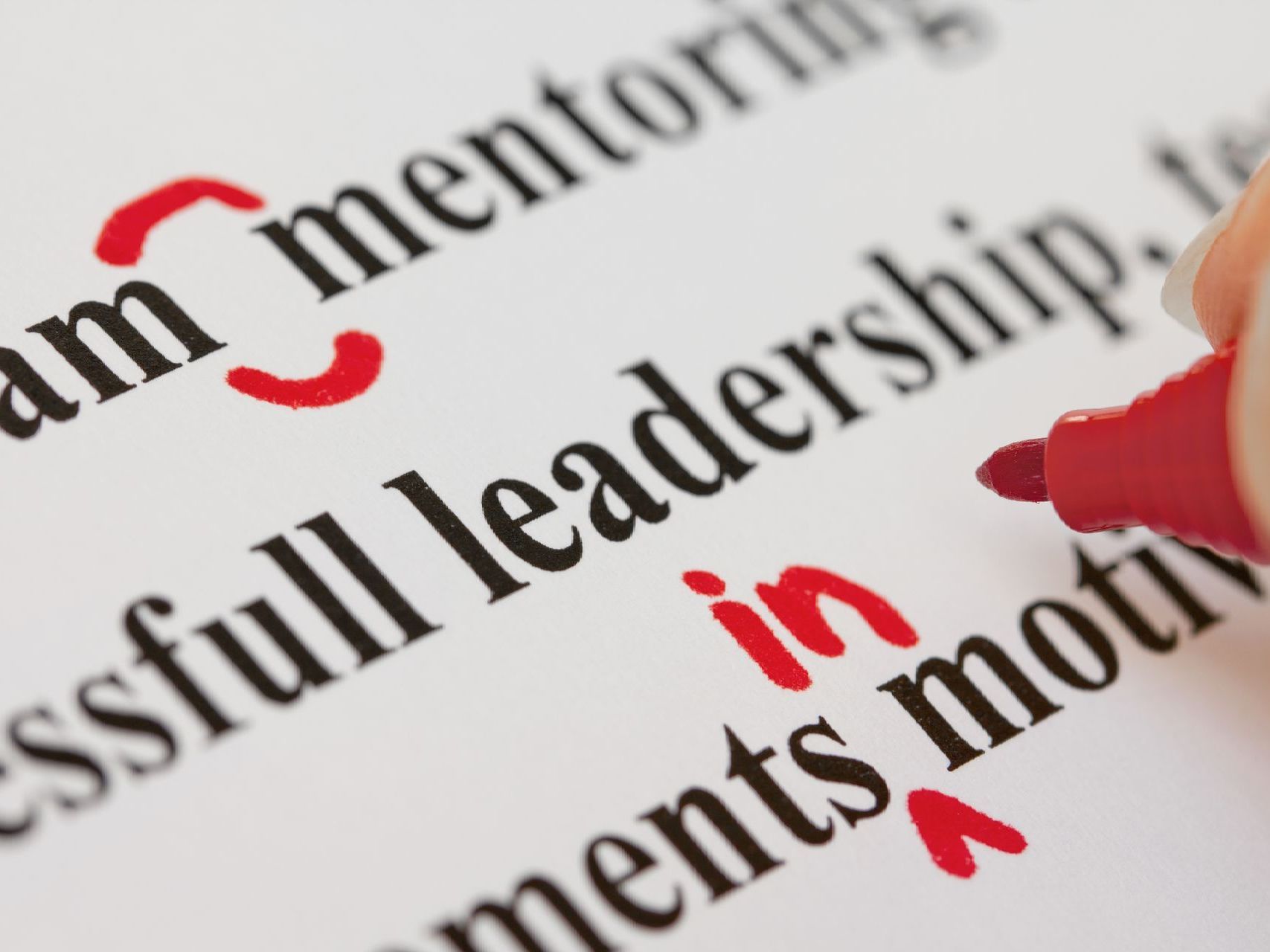 A person is highlighting the word leadership in red