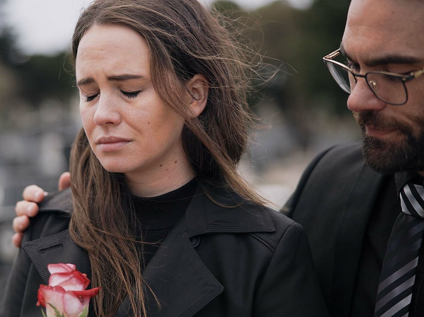A man is comforting a woman who is crying at a funeral.