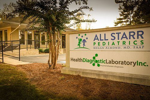 All Starr Pediatrics sign outside building at dusk, with trees and a walkway nearby