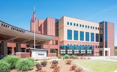 Hospital entrance with brick facade, covered drop-off area, and an American flag.