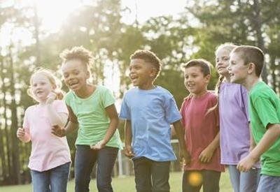 Children in colorful shirts running together outdoors in a sunny park