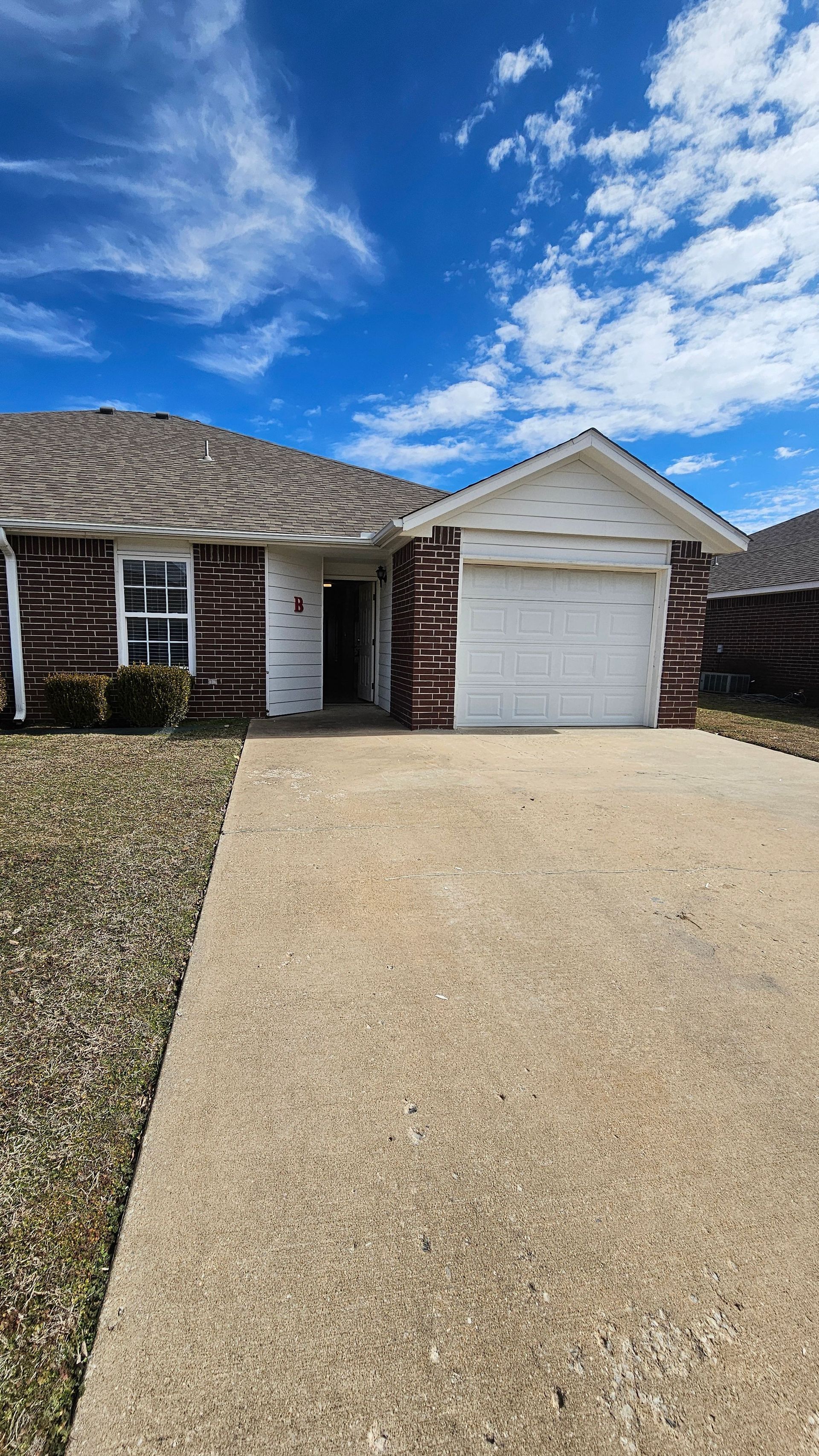 A brick house with a white garage door and a driveway.