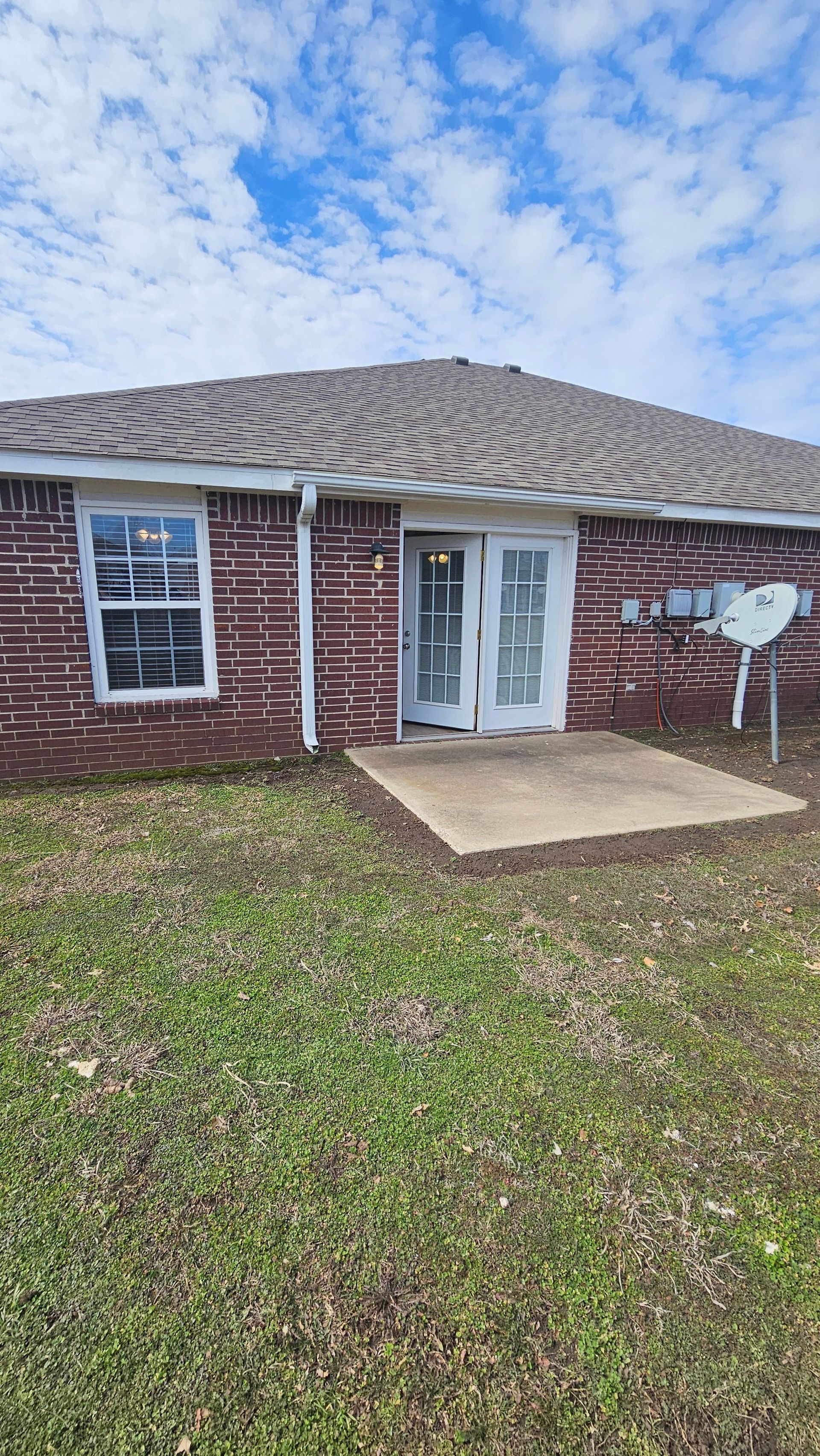 A brick house with a satellite dish in the backyard.