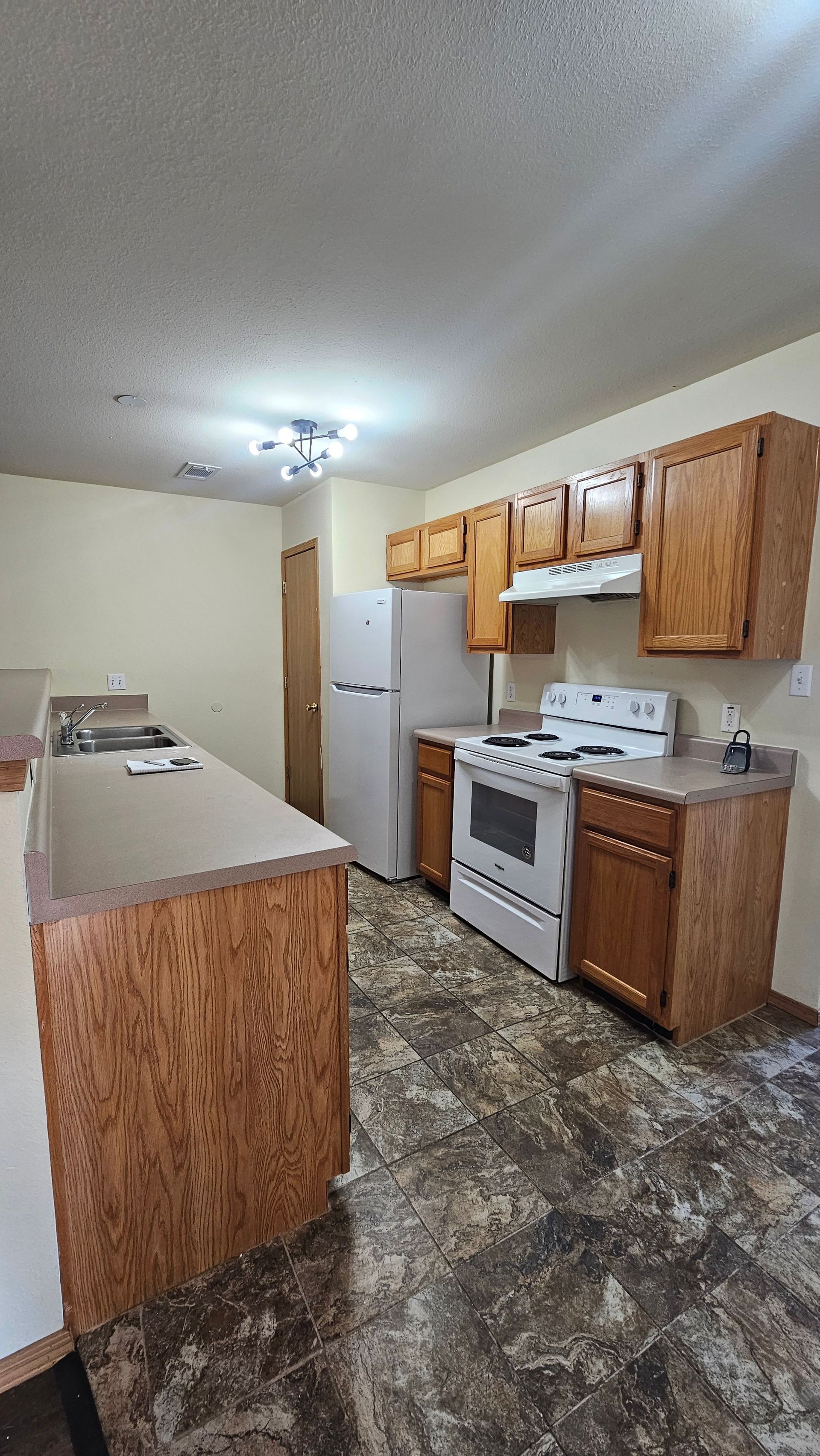 A kitchen with a stove , refrigerator , and sink.