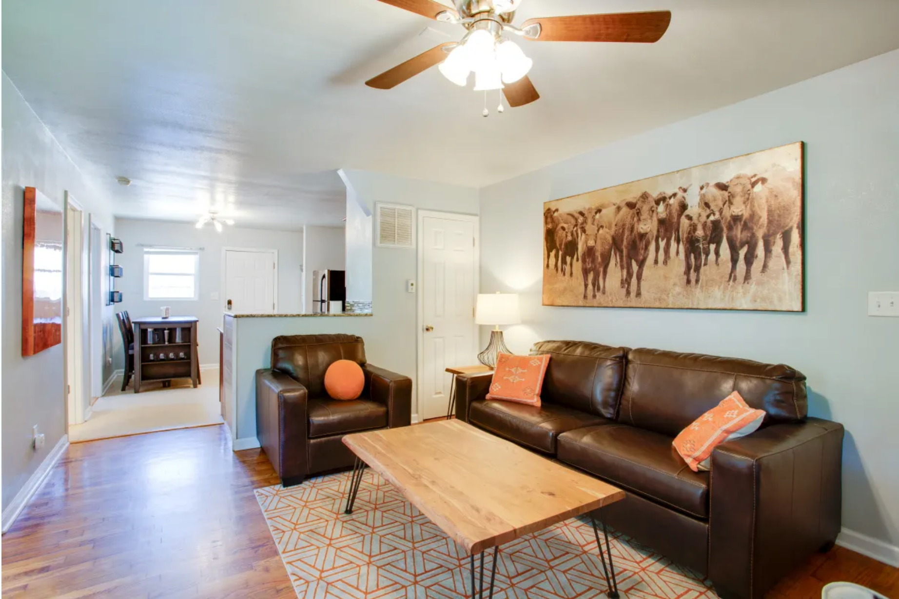 A living room with a couch , chair , coffee table and ceiling fan.