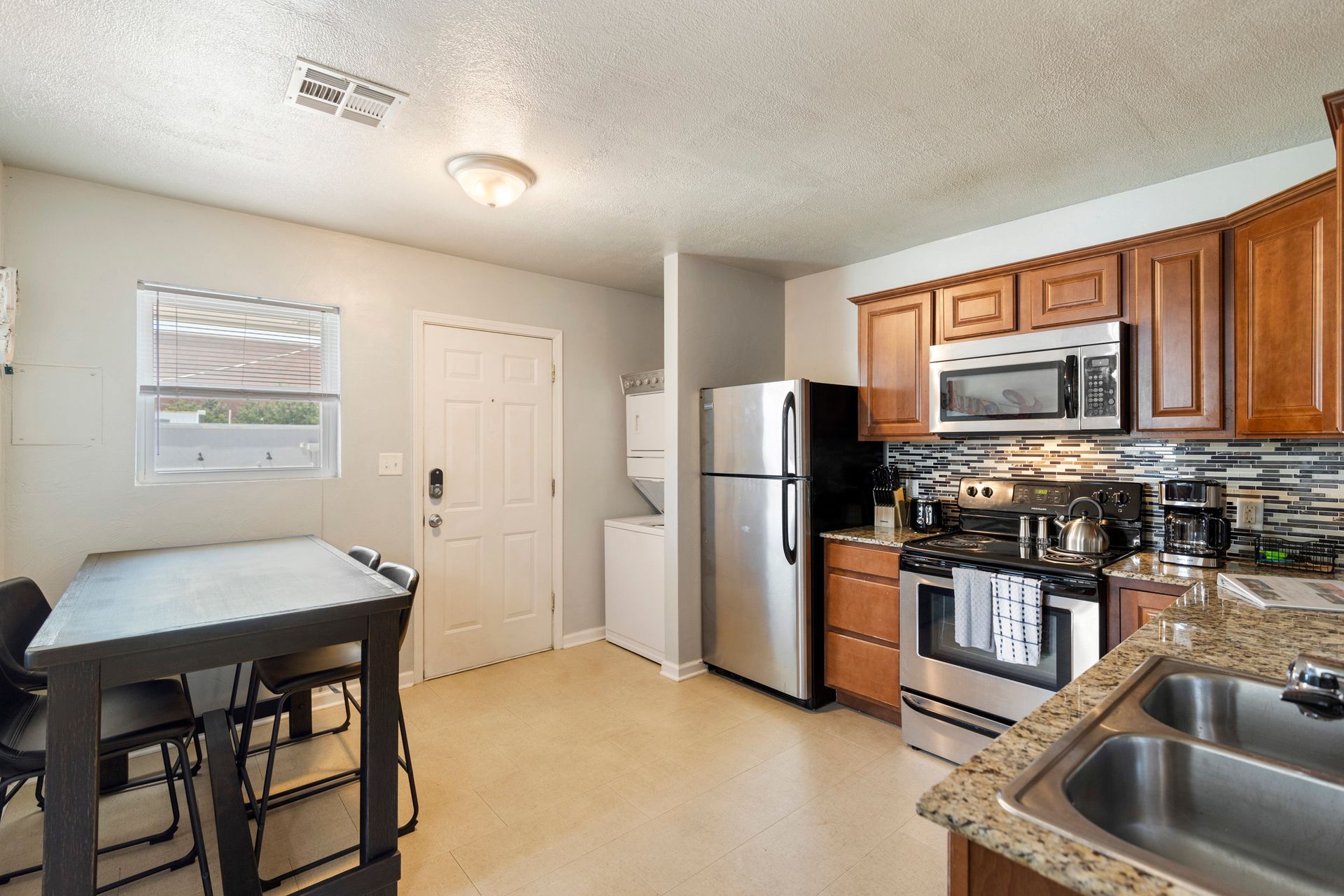 A kitchen with a refrigerator , stove , microwave , sink and table.