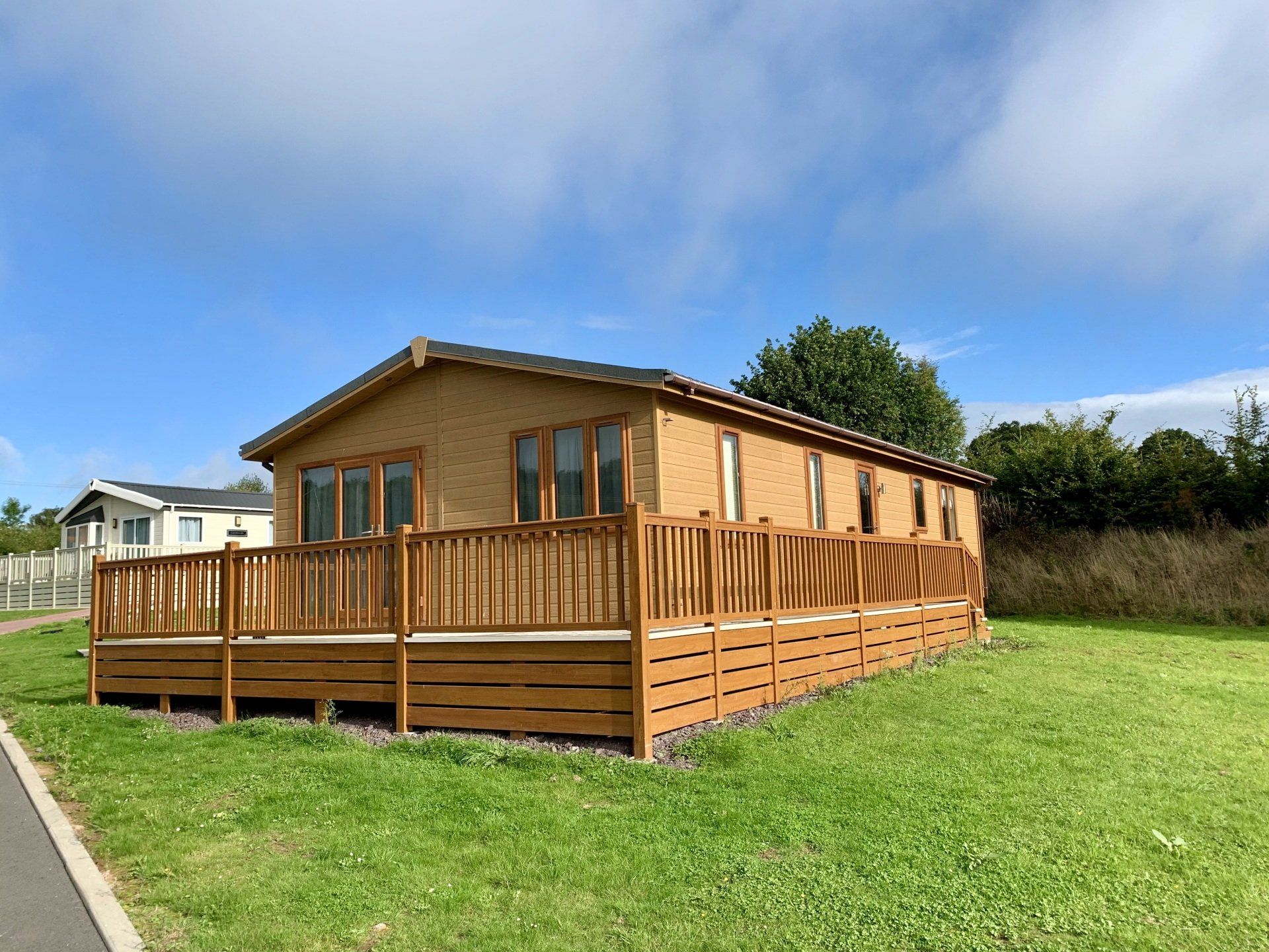 A large house with a wooden deck is sitting on top of a lush green field.