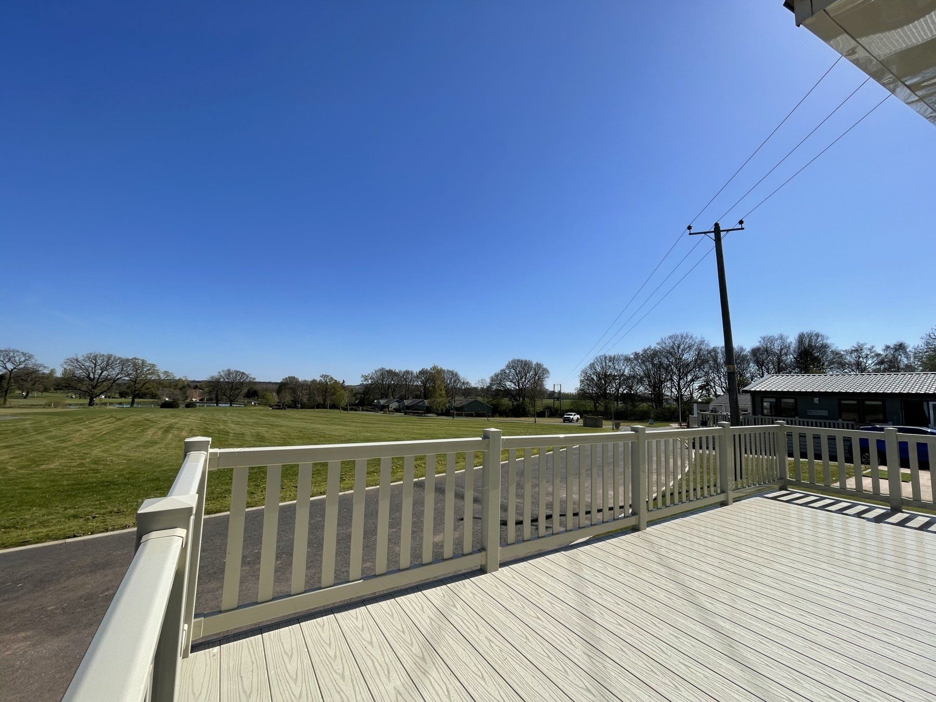 A deck with a fence and a view of a field