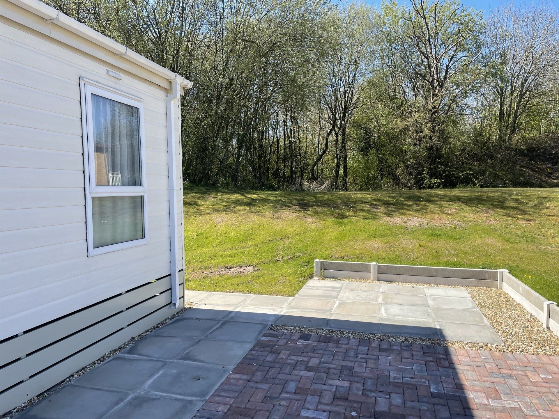 A white house with a brick driveway and a patio in front of it.