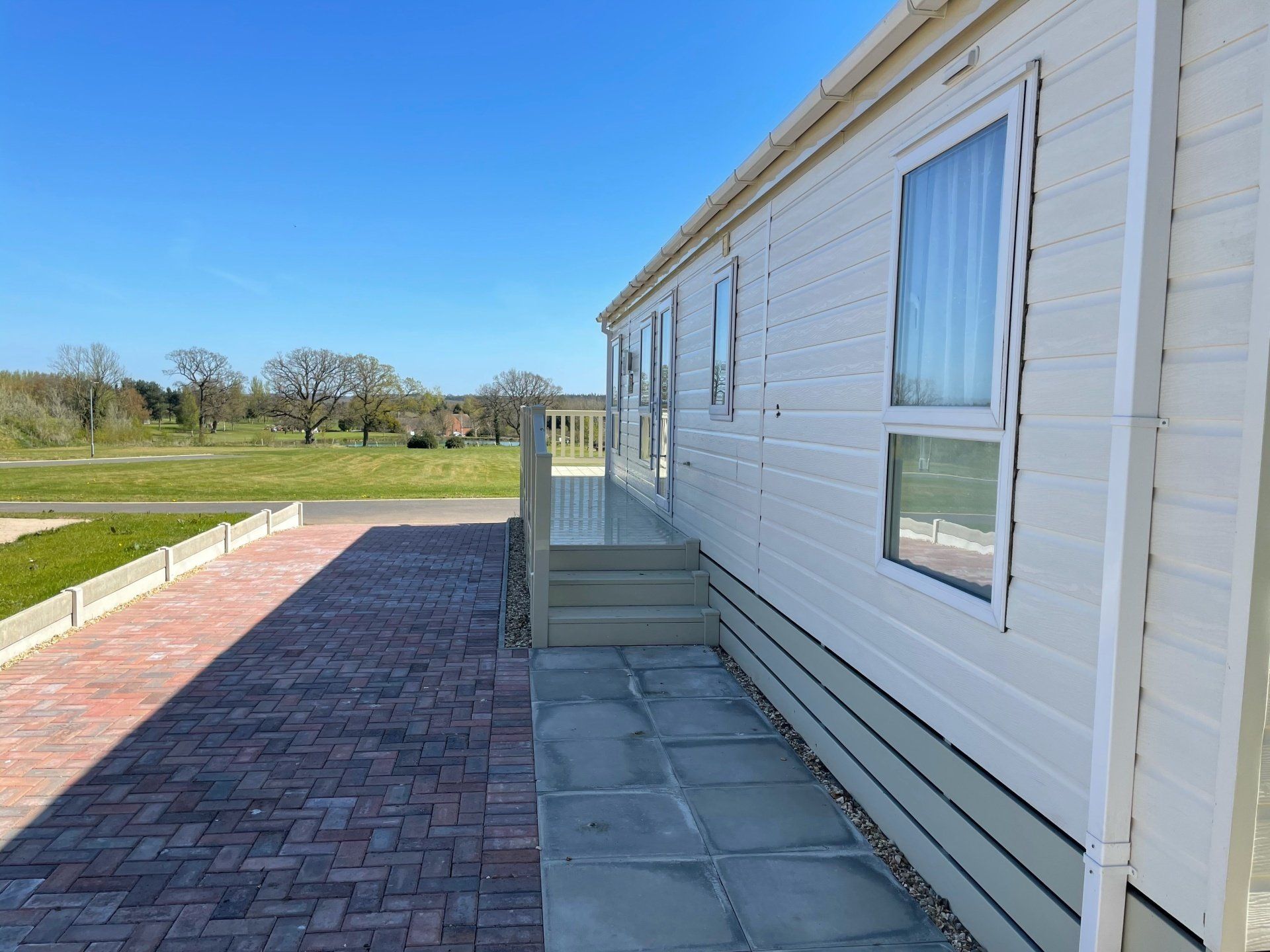 A white mobile home with a brick walkway leading to it