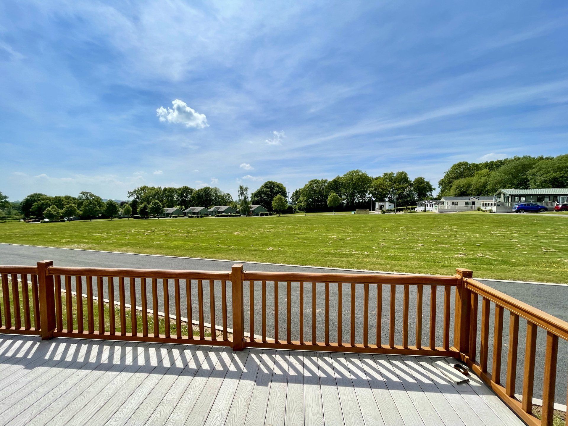 A view of a field from a deck with a wooden railing.