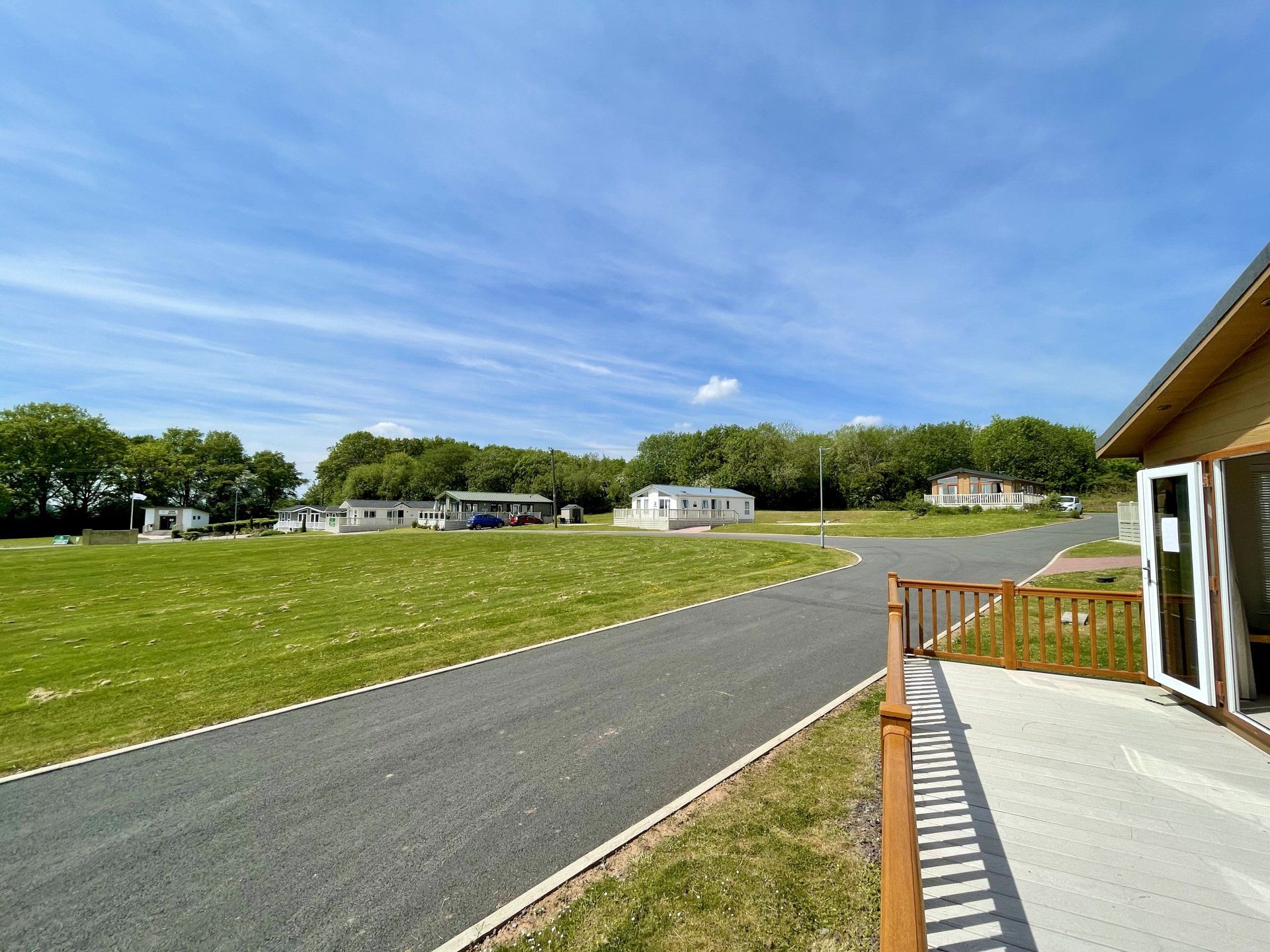 A house is sitting on the side of a road next to a grassy field.