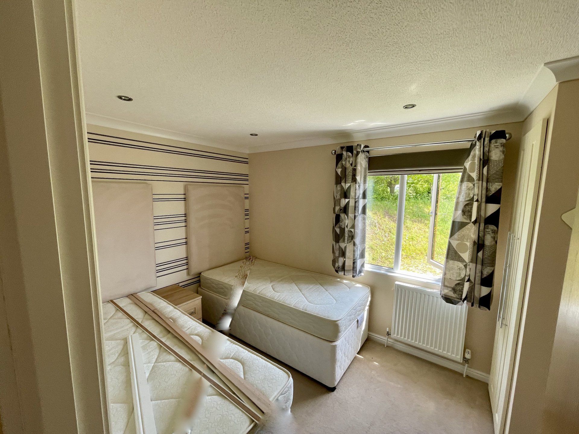 A bedroom with two beds and a window with curtains.
