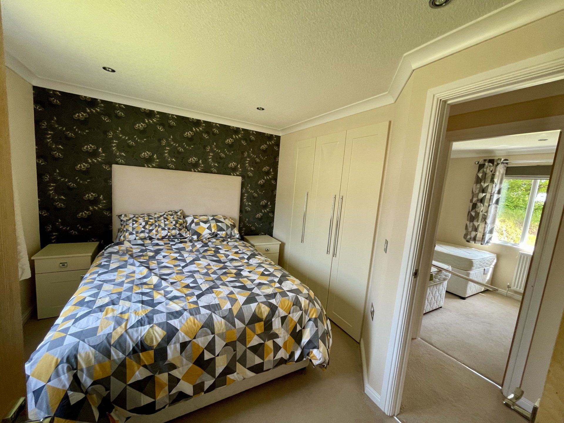 A bedroom with a bed , nightstands , and a doorway leading to another room.
