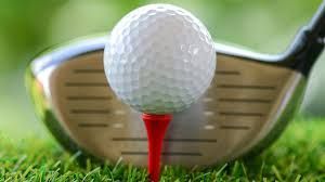 A golf ball is on a red tee next to a golf club.
