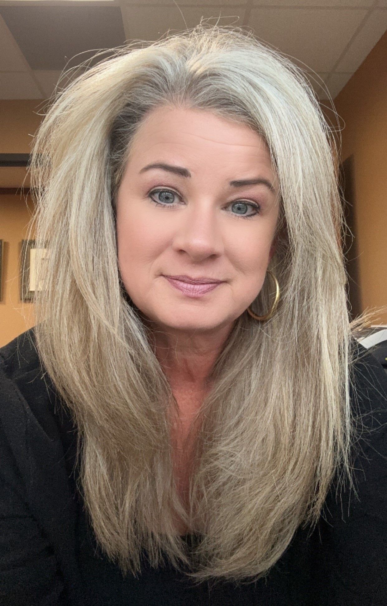 A woman with long blonde hair and blue eyes is smiling for the camera.