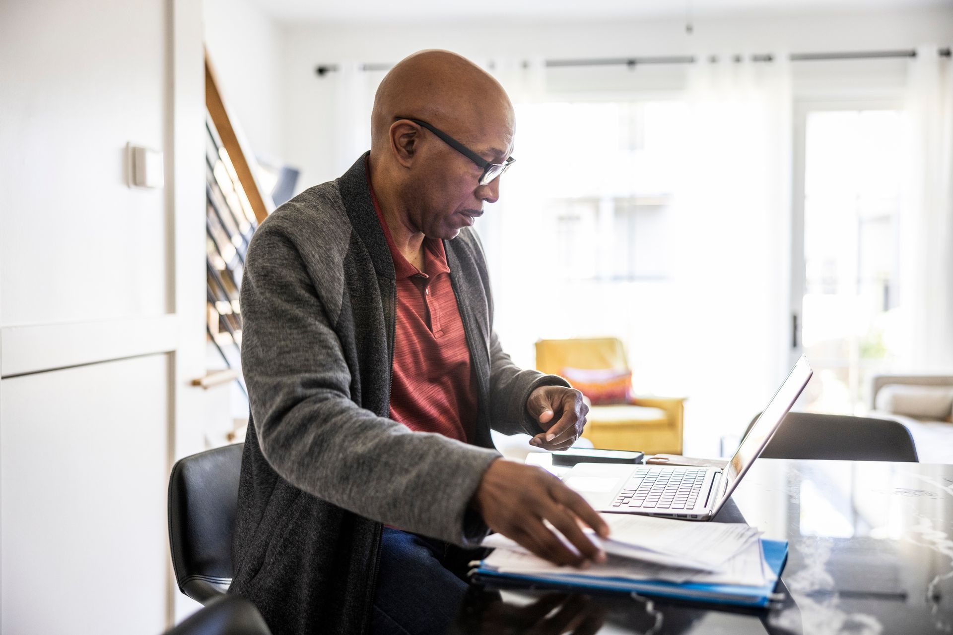 A man is sitting at a table using a laptop computer.