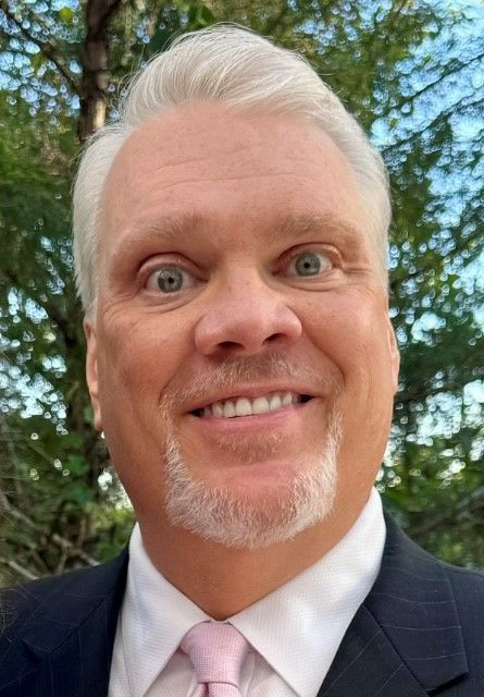 A man in a suit and tie is smiling for the camera.