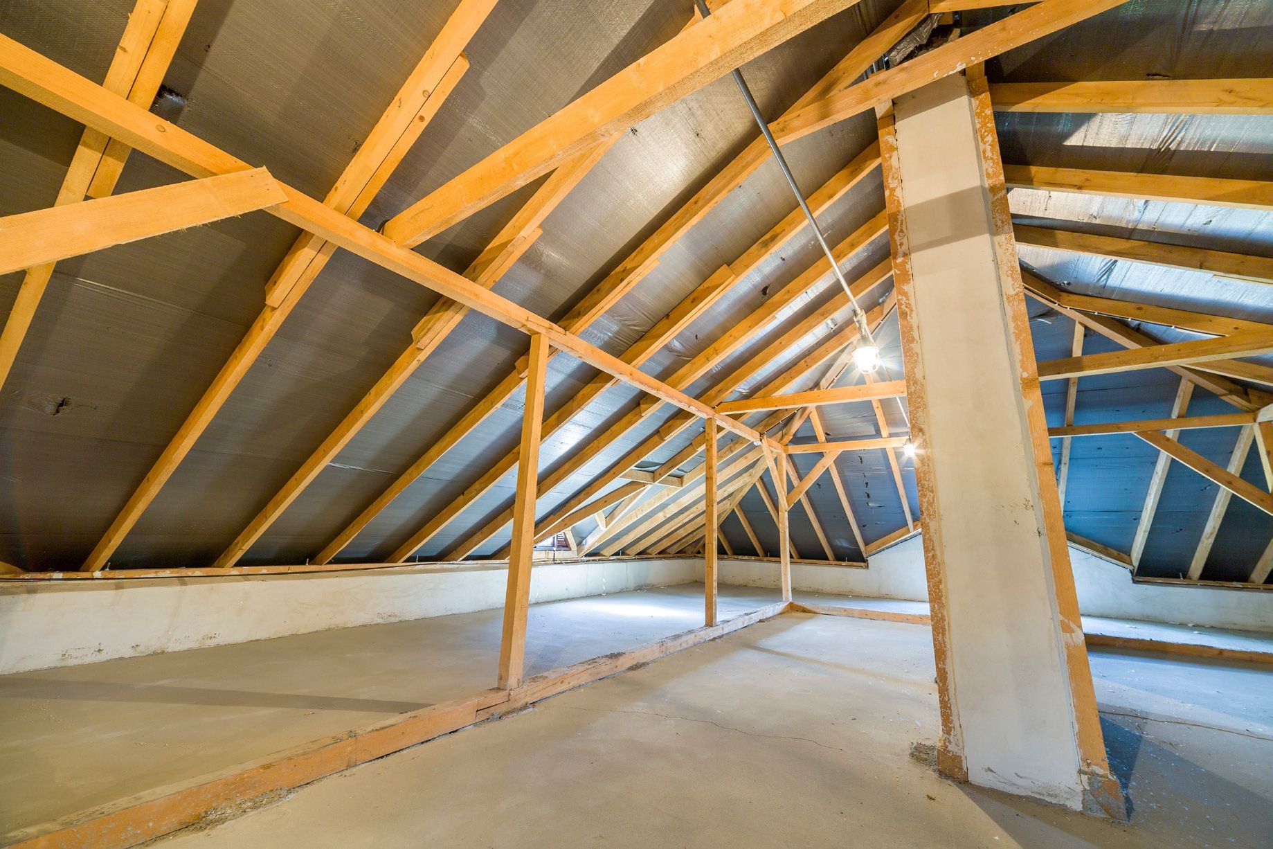 An empty attic with wooden beams and a chimney.