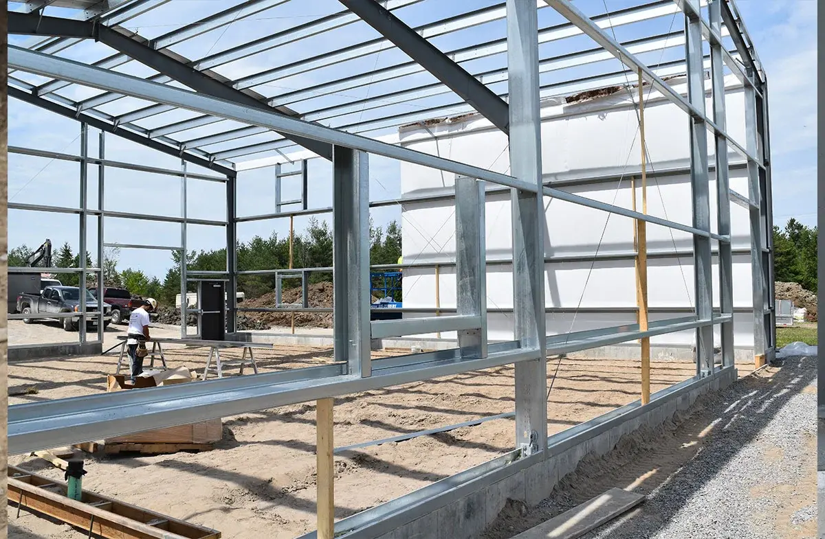 A large metal structure is being built on a dirt field.