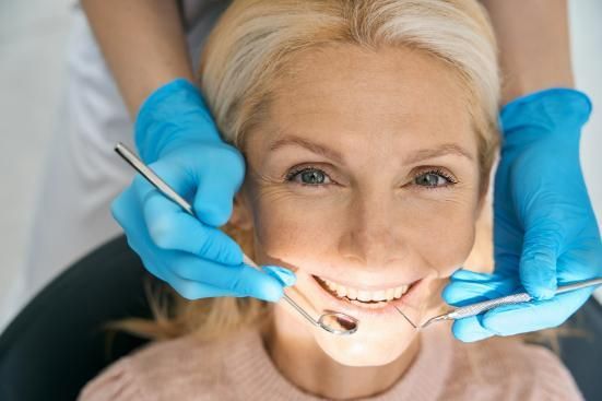 A Woman Is Smiling While Having Her Teeth Examined by A Dentist — Tweed City Dental in Tweed Heads South, NSW