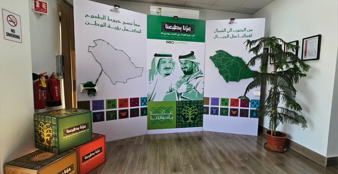 Display for Saudi National Day: map art, portraits, green/white colors, and plant.