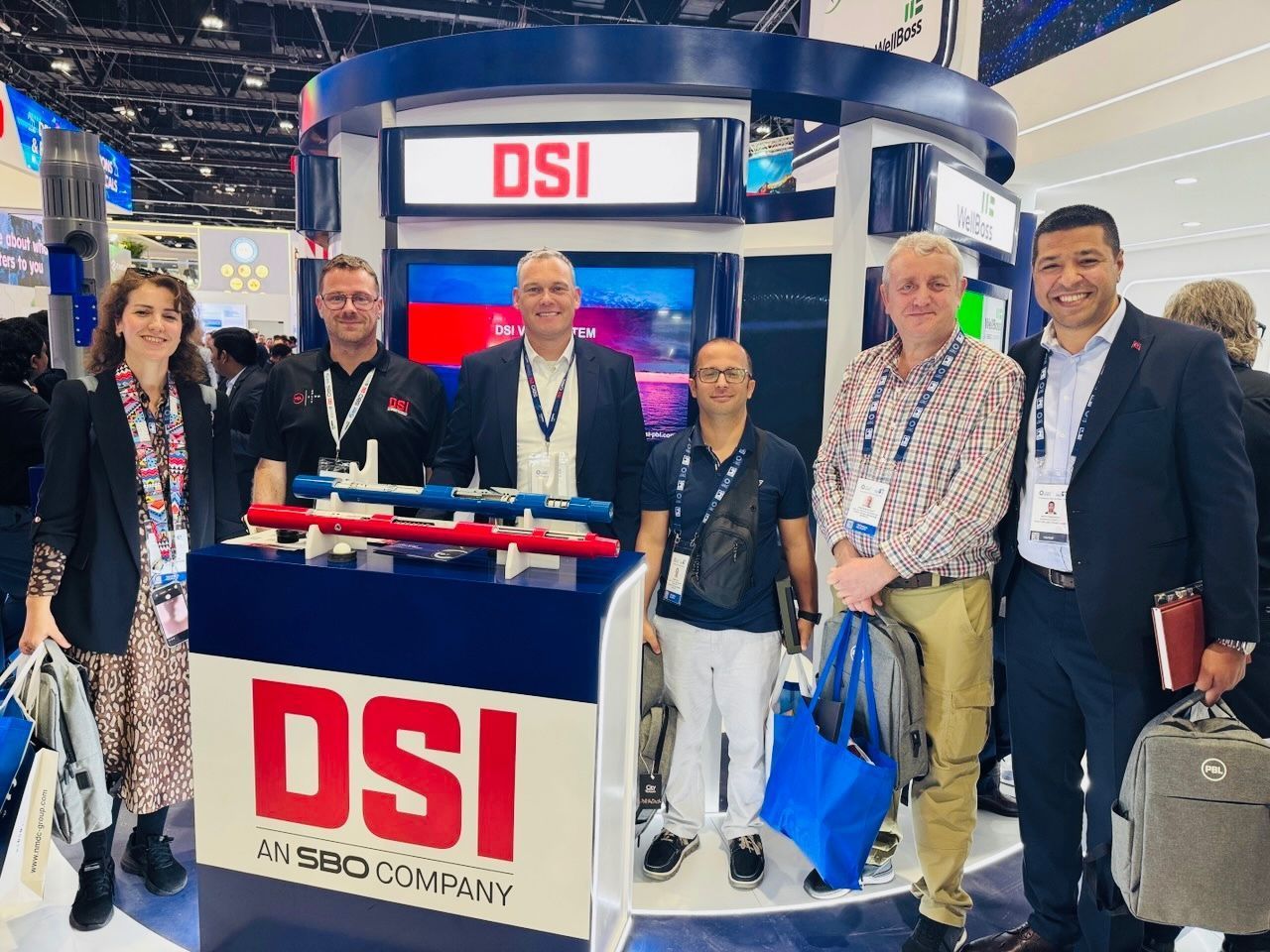 People at a DSI booth, with products displayed. The booth has a blue, white, and red logo. People wear name tags.