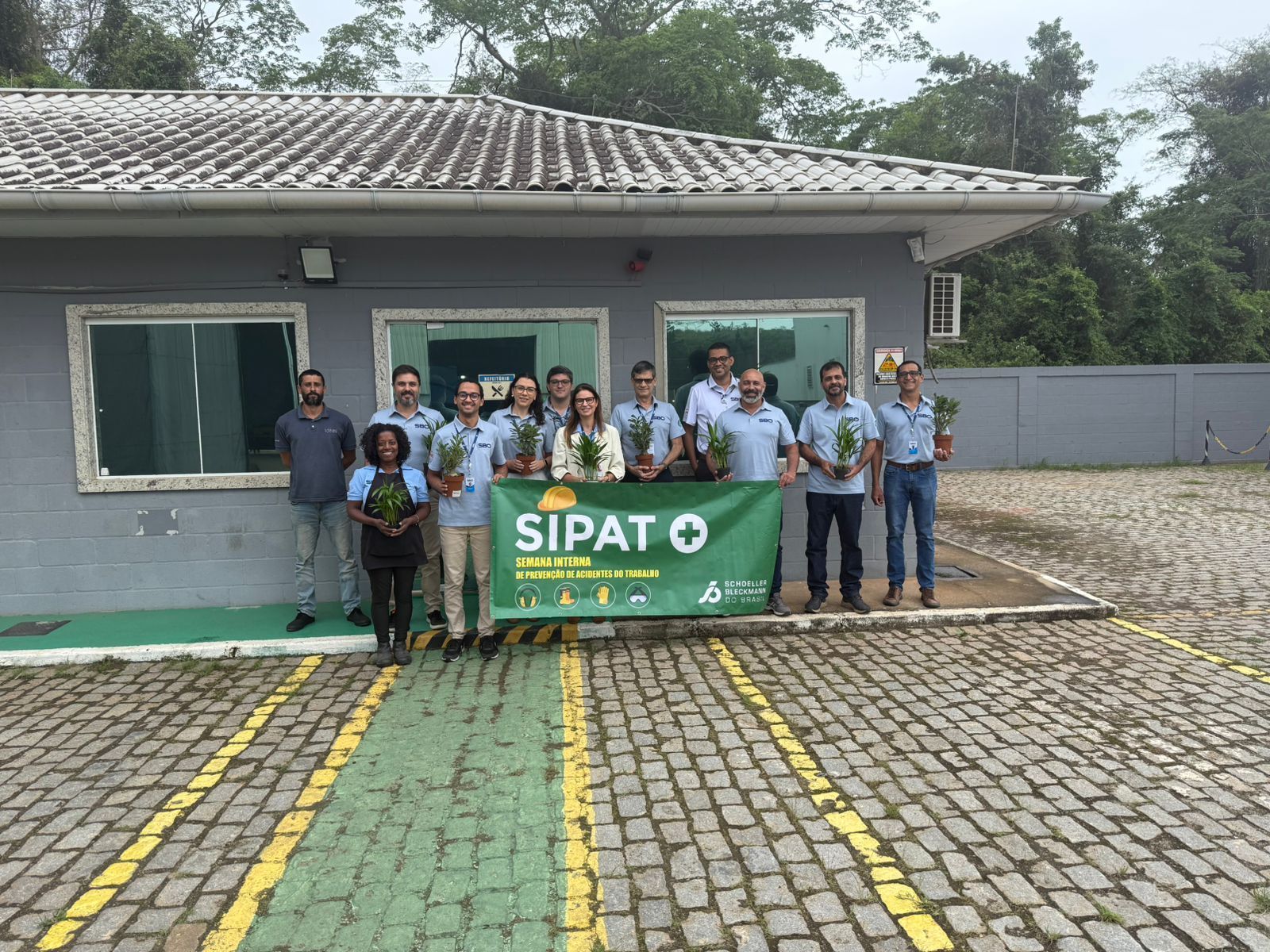 Group of people holding plants in front of a building with a