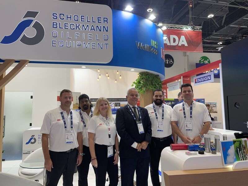 A group of people standing in front of a sign that says schoeller beckmann oilfield equipment