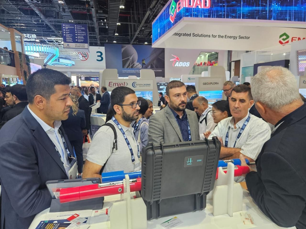 A group of men are standing around a table at a convention.