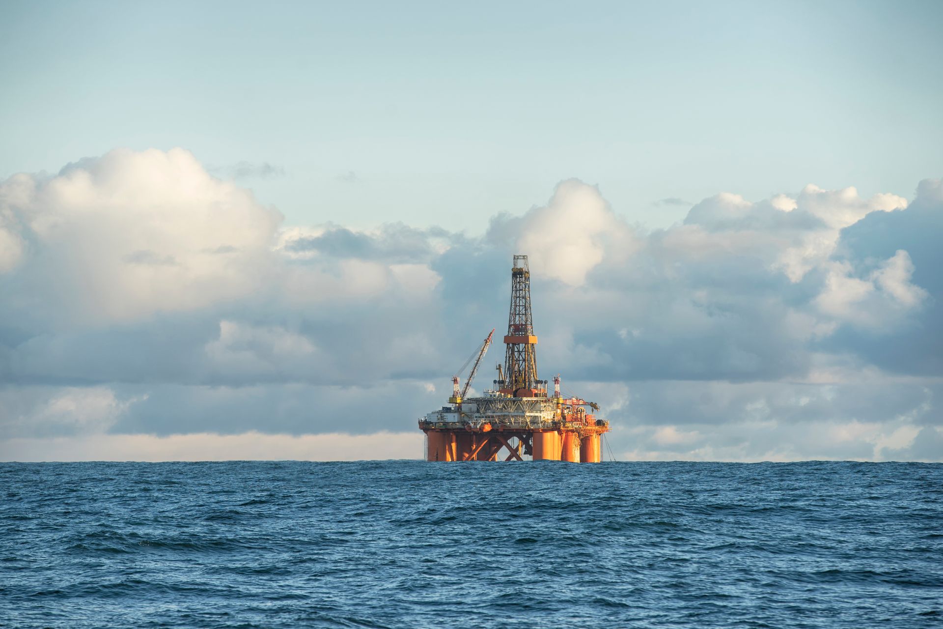 Oil rig in ocean under cloudy sky.