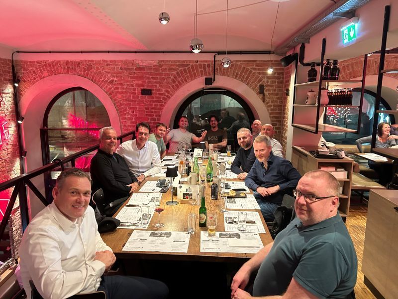 A group of men are sitting at a long table in a restaurant.