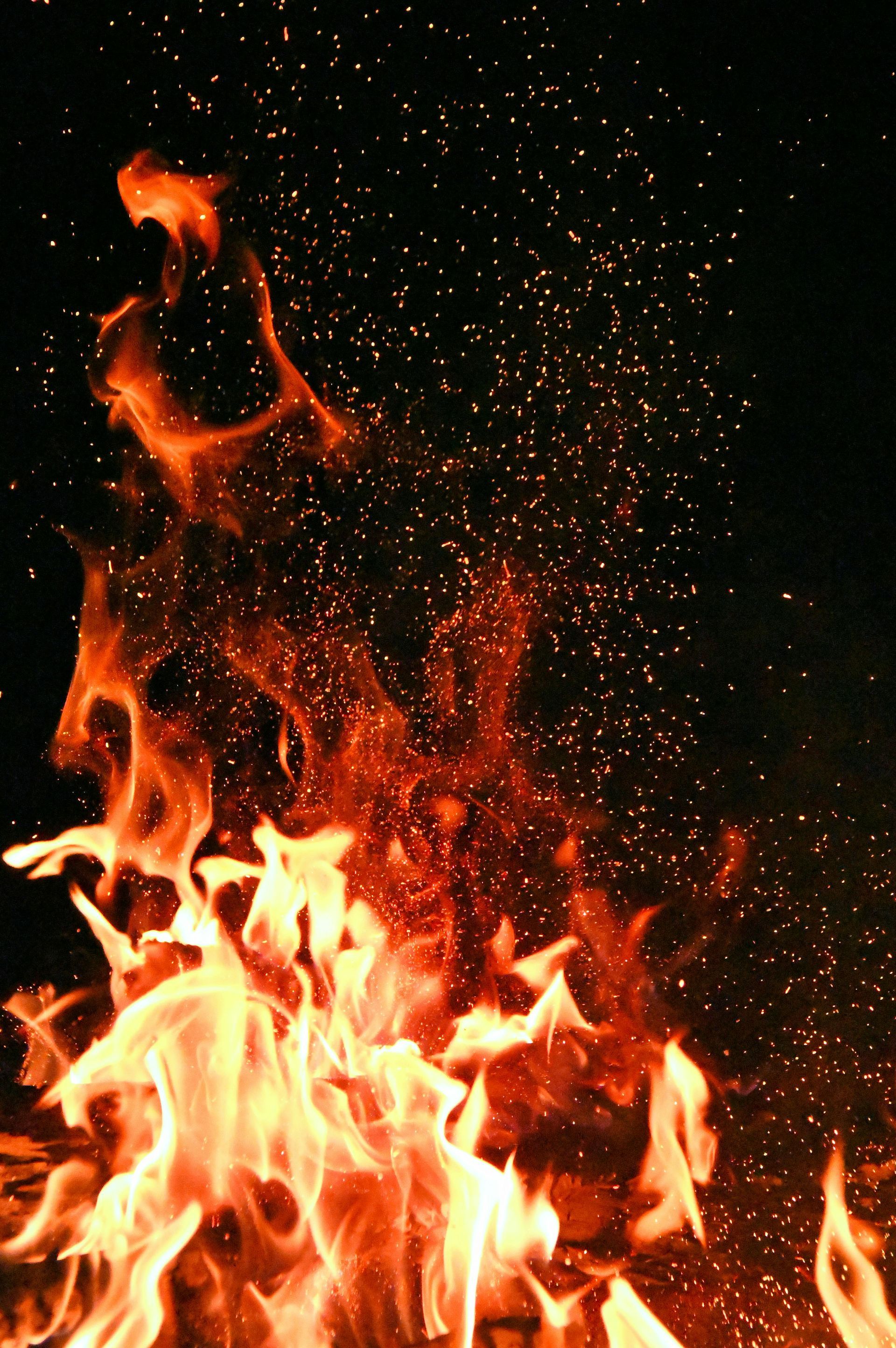 A close up of a fire with sparks coming out of it in the dark.
