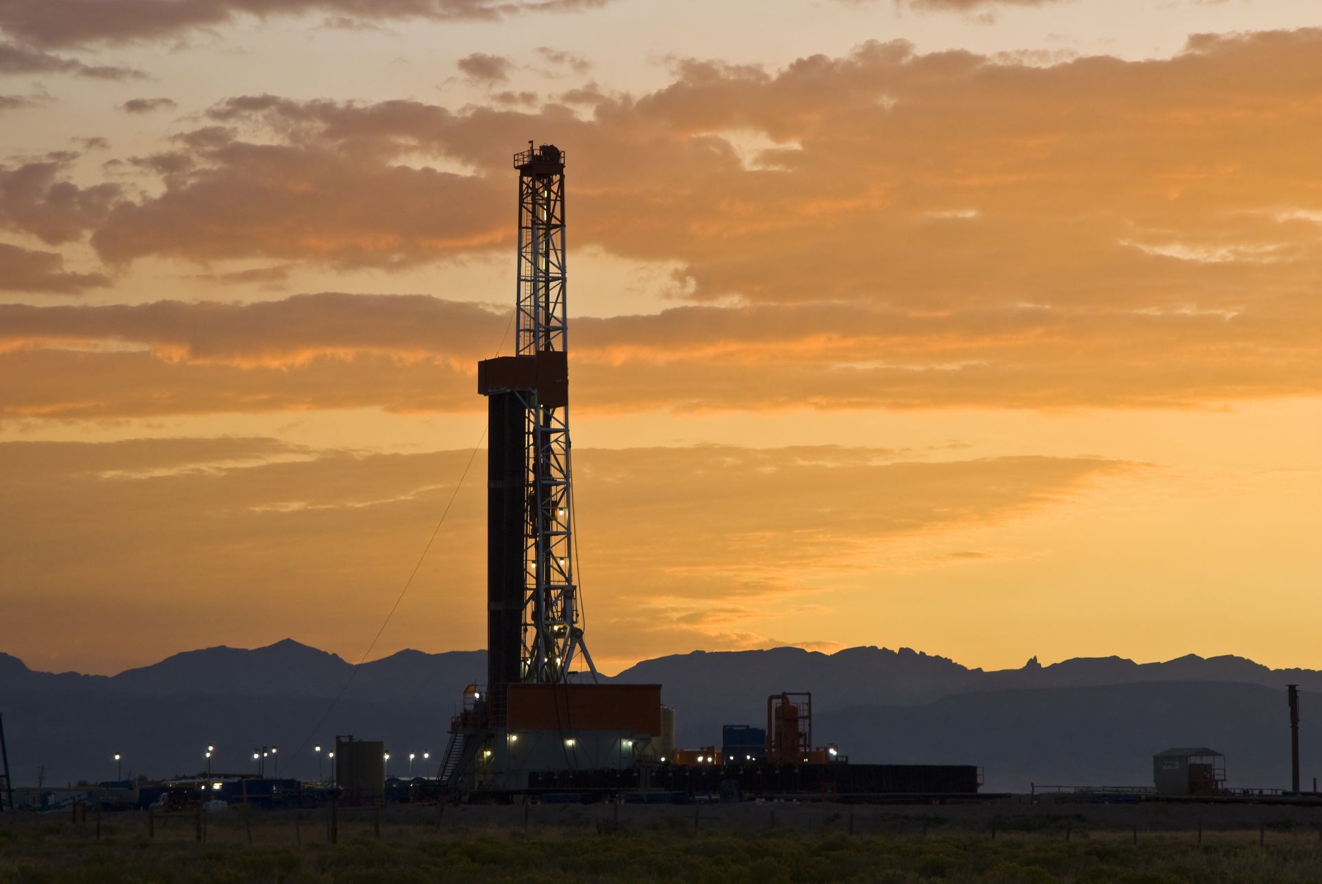 A large oil rig in the middle of a field at sunset.