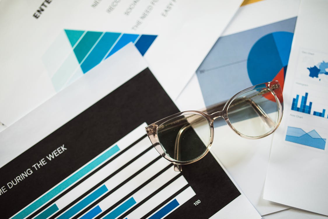A pair of glasses is sitting on top of a pile of papers.